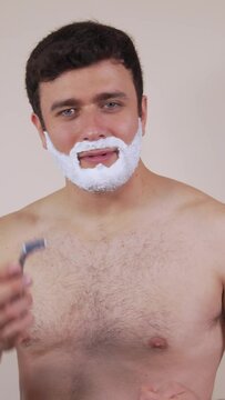 Vertical video.White man, shaving, recommending shaving with hand razor.