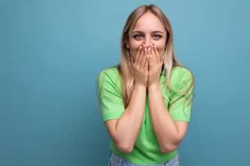 young happy shocked woman in casual outfit covered her mouth in surprise on a blue isolated background