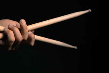 hands holding drumsticks on a dark background