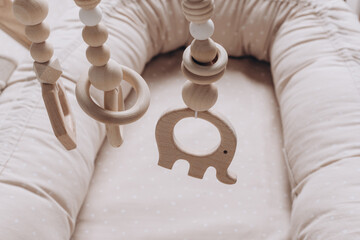 Wooden arc with toys over cocoon, nest for newborns in child cribs in nursery. Childhood concept,...