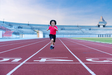 Fototapeta premium Little girl at athletics competition race. A girl running in stadium.