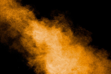 Abstract explosion of orange dust on black background.Freeze motion of orange powder burst.