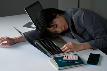 残業で疲れて眠るビジネスウーマン