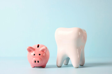 Pink piggy bank with tooth model on blue background. Investing in dental health care.