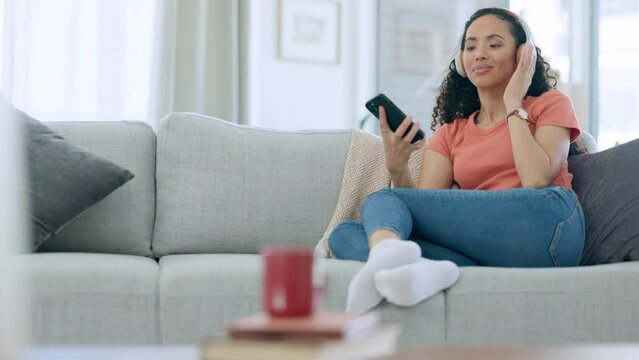 Headphones, phone and happy woman on couch listening to music for mental health, wellness or self care at home. Calm, relaxing and gen z person on sofa, cellphone and audio technology in apartment