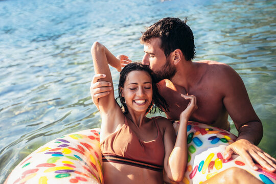 Young couple with inflatable rings having fun at the sea on summer vacation.