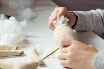 Close up cropped woman, tailor hands stitching ans sewing soft toys in workshop. Small business, creative occupation. Shop, atelier for children, making stuffed soft toys, filling them with cotton