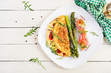 Ketogenic breakfast. Omelette with tomatoes, red onion, sandwich with salmon and roasted asparagus. Italian frittata. Keto, ketogenic lunch. Top view, flat lay