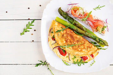 Ketogenic breakfast. Omelette with tomatoes, red onion, sandwich with salmon and roasted asparagus. Italian frittata. Keto, ketogenic lunch. Top view, flat lay