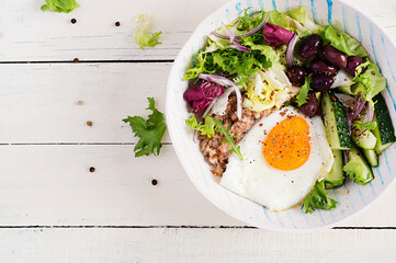 Breakfast wheat porridge with  roasted egg, cucumber and olives. Healthy balanced food. Top view, flat lay