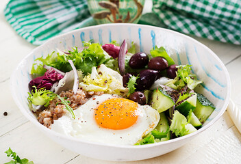 Breakfast wheat porridge with  roasted egg, cucumber and olives. Healthy balanced food.