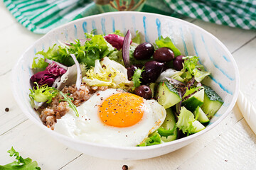 Breakfast wheat porridge with  roasted egg, cucumber and olives. Healthy balanced food.