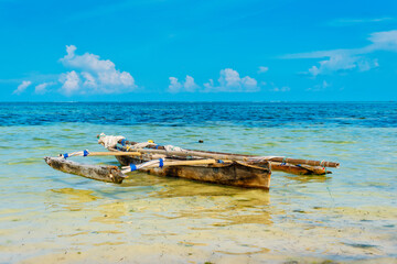 Experience the beauty of a traditional Zanzibar fishing boat as it rests in the clear waters near...