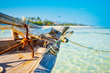 Experience the beauty of a traditional Zanzibar fishing boat as it rests in the clear waters near the beach of a tropical island, ideal for summer travel and fishing boats.