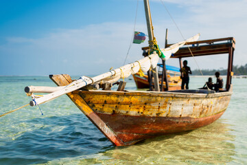 Experience the beauty of a traditional Zanzibar fishing boat as it rests in the clear waters near the beach of a tropical island, ideal for summer travel and fishing boats.