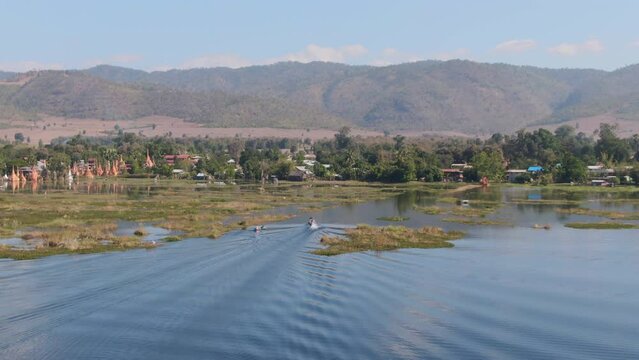 Aerial view showing traditional long-tail boat arriving Taw Mwe Khaung Pagoda on Moebyel Lake, Myanmar. Beautiful landscape shot during sunny day