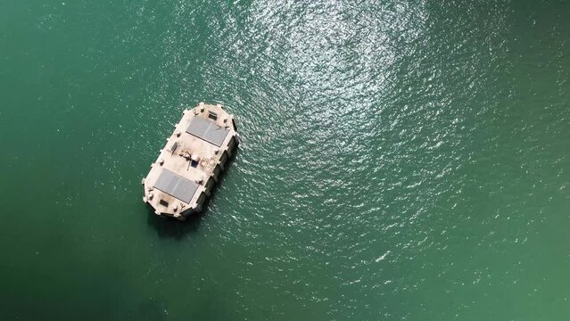Aerial Birdseye view above Fawley power station cooling water outlet surrounded by shimmering sunlit emerald ocean