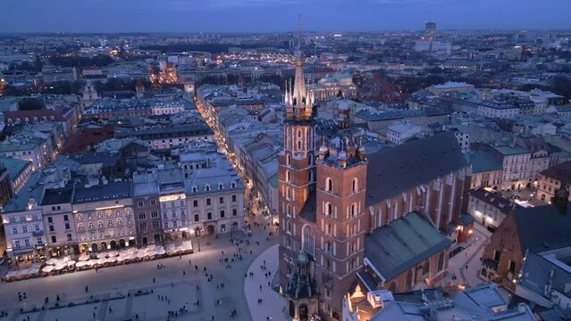 Krakow Main Market Square aerial view in the night. Illuminated building of Saint Mary's (Mariacki) and Florianska Street with Florianska Gate in the background  