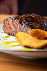 Close up Gourmet Main Dish with Grilled Pork Rib and Fried Potatoes on White Plate. S