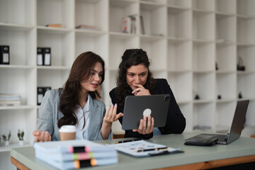 Two smart multiethnic business people working together with laptop while working on project in office