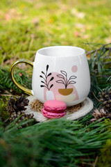 Coffee mug and colorful macaroon cookies, picnic in the forest