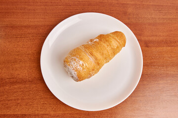 Puff pastry tube with cream on a white plate.