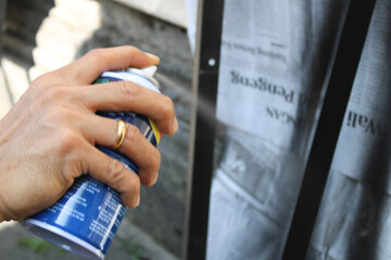 A worker painting steel angle or angle iron in black with spray paint or aerosol paint to create shelves