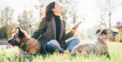 Woman walk with two dog, using phone in the park