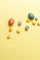 Colored eggs of different sizes on a yellow background. Symbol of the Easter holiday. Easter background. Flat lay