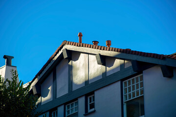 Suburban house in modern area with sunrise beams hitting double gable style roof with white exterior color daytime