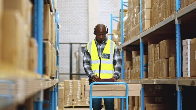 Black warehouse worker picking orders with the use of a headset and voice directed technology