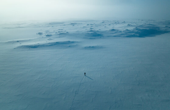 Solitude in the Snow: Aerial View of Lone Walker in White Winter Wonderland