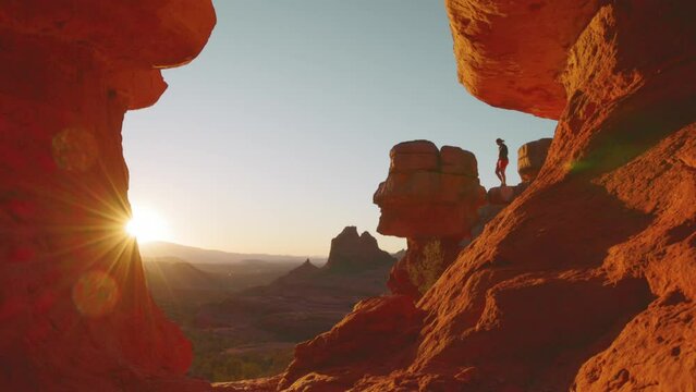 Young woman walks onto insane rock outcropping to watch the sun set in Sedona