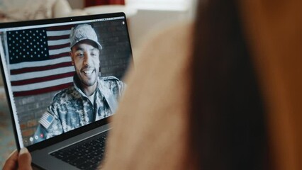 Military family connects with deployed dad over a video call at home. Wife video calling her husband in the army for a family catch up with the kids. Patriotic family using technology to communicate.