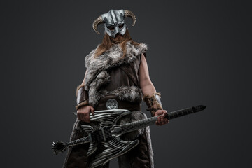Portrait of scandinavian warrior with electric guitar and horned helmet looking at camera.