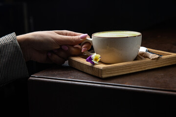 A cup of matcha latte with a spoon on a wooden tray