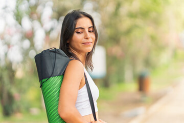 Young sporty woman, posing with her mat over her shoulder