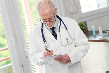 Senior doctor taking notes on clipboard