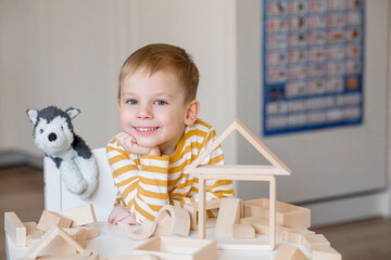 A little boy of 3 years old is playing a developing logistics constructor. Children's wooden toys....