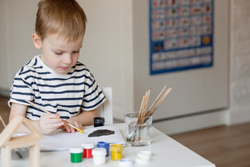 A little boy of 3 years old paints on paper. Children's games for child development. Kindergarten.