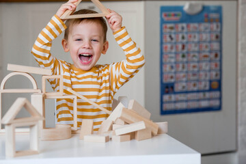 A little boy of 3 years old is playing a developing logistics constructor. Children's wooden toys....