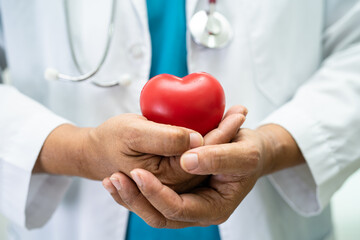 Doctor holding a red heart in hospital ward, healthy strong medical concept.