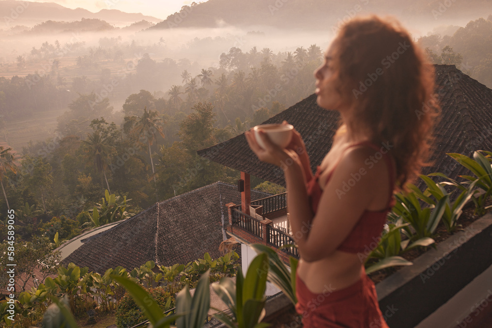 Wall mural Woman enjoys a relaxing yoga retreat at a beautiful Bali resort with stunning views of the sunrise and Agung volcano. Travel and wellness concept.