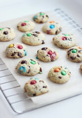 Stack of children's homemade cookies with colorful chocolate candies in a sugar glaze on a white light background. Selective focus. High quality photo