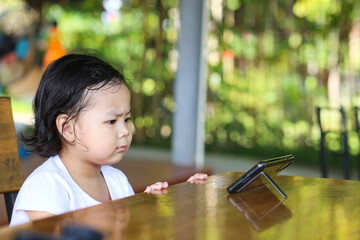 An Asian girl watching cartoon on a smart phone. 