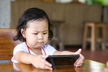 An Asian girl watching cartoon on a smart phone. 