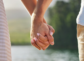 Holding hands, love and couple at lake outdoors for commitment, trust and support. Romantic date,...