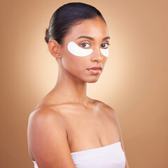 Skincare, eye patch and beauty with Indian woman for facial, spa treatment and glow. Self care, cosmetics and hydration with female model isolated on brown background for mask, product and youth