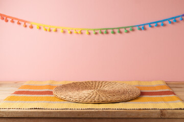 Empty wooden table with wicker place mat over pink wall  background. Mexican party mock up for design and product display - 584601020