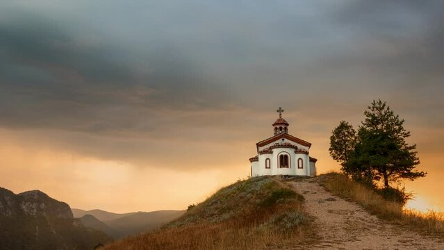 A small Orthodox chapel on the top of a hill during a beautiful sunset with a bit of rain